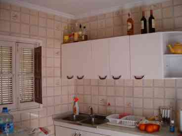 Bright and airy kitchen equipped with gas cooker, fridge and washing machine, also contains a small extendable dining table. Door leading to courtyard.
