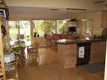 A bar and matching glass top table highlight the entertainment room one step below and connecting the kitchen.