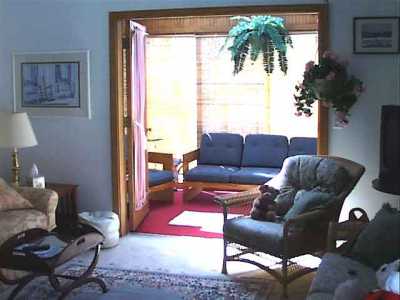 Living Room area toward sunroom, open ceiling, wall to wall carpet and 8\' slider to front deck