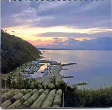 View from the garden of the residence overlooking the port and the beach at sunset.