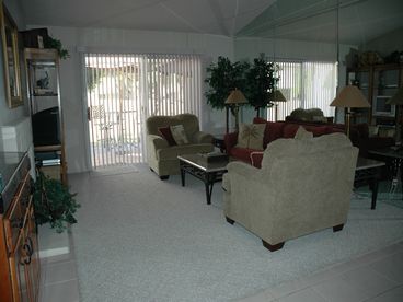 Living rm boasts w/ vaulted ceilings a flat screen tv, wt bar, mirrored wall and