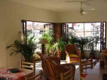 This is our Unit 2 living room, featuring wrap-around balconies, lots of plants, brand new rattan furniture and good views of the mountains to the south