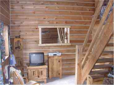 Front door to the left, kitchen area to the right. Stairs going up to loft. Rest of living room below photo includes a sofa sleeper, 2 rockers, stereo, etc.
Local handcrafted traditional square log cabin!