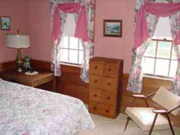 Bedroom with one queen size bed, two dressers and a closet; view of the harbor.