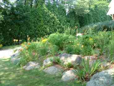 rock garden island in front of house with circular driveway