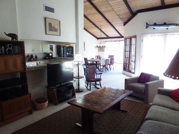 Living room, deck doors open, dining at the end to the left, and kitchen partially shown