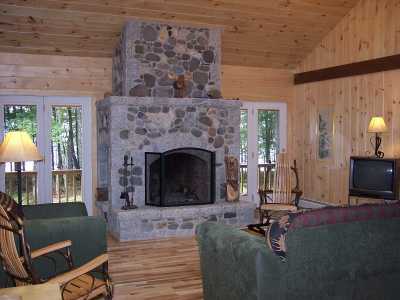 View of the living room and a one of a kind fireplace. French doors look out to the lake. Two skylights brighten the room.