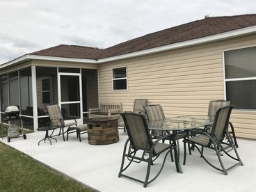 Screened lanai and large patio with fire pit, dinette, and gas grill