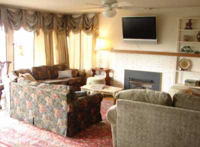 Bright living room with sliding door to adjacent deck offers plenty of comfortable seating, a gas fireplace, and plasma TV.