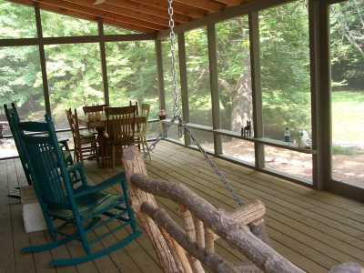 Large screened porch with table & chairs for creekside dining, rockers, and twig porch swing.