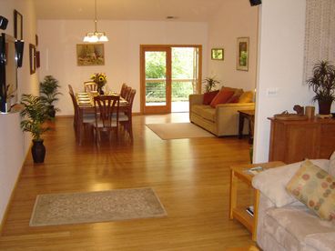 Open living & dining room with high ceilings, glass doors out to deck.