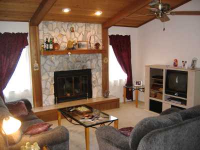 Living Room with stone fireplace, TV, DVD and ceiling fans.