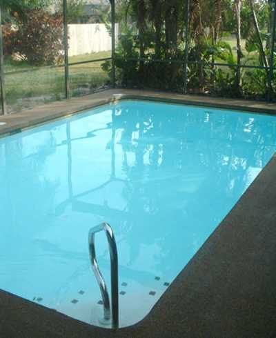 In-ground swimming pool with large screened lanai area, BBQ grill, and horseshoe pits in backyard.