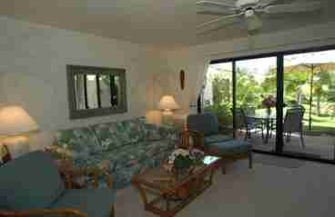 Living area looking out towards tropical garden setting lanai with dining table and chairs.