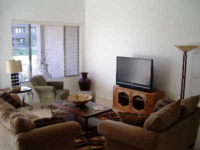 The comfortable living room has a sliding glass door to the patio. The kitchen is to the right, dining area to the left.