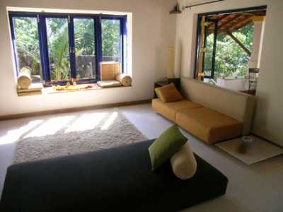 A view of part of the living room area showing the 3 seater and large bay window which overlooks a lotus pond.