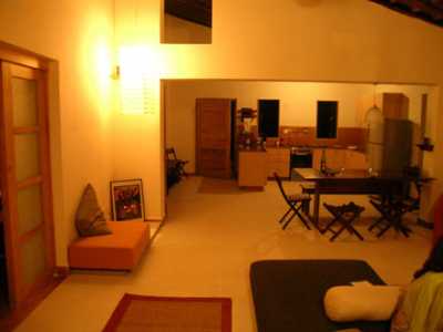 A view of the Dining and open kitchen area during the evening. The kitchen at the rear opens out to a barbeque sit out and a landscaped garden facing the valley forest.