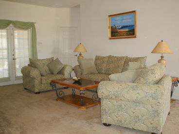 Family lounge with comfy seating for relaxing in front of the TV after a long day at the theme parks. Patio doors onto the lanai and pool area.