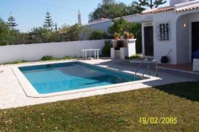 Beautifull swimming-pool surrounded by grass with barbeque in the garden.