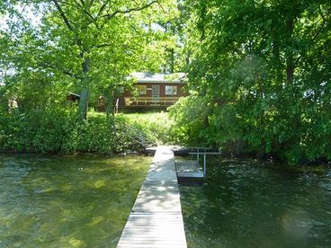 Nice and green...  trees, foliage, and the clear water with out weeds.  Canoe is included with the rental, and room to more a fishing boat or skiboat.  You\'ll be sitting on the deck to drink your coffee and tea, with newspaper or a good book (and keep an eye on the kids -- you know were they\'ll be).  If you sit still, the chickadees will come eat sunflower seeds out of your hand. 
