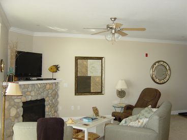 Large living room with river rock gas fireplace, Plasma TV, and relaxing massage chair.