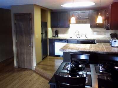 Kitchen with granite tile counters and travertine backsplash. Stainless appliances. Open to Living room. Bamboo floors in Kitchen and Living Room.