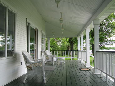 One of the Main Cottage\'s finest features is the large wrap around porch with magnificent views of the lake.  Dim the overhead lighting and enjoy your family\'s nightly dinner from the large wrap around porch.  Wicker furniture and two white wood rockers offer additional seating! 