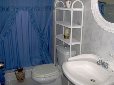 The ocean mist bathroom with shower,toilet and basin in ceramic white with baby blue decorations and flowing ocean tiles full linens
