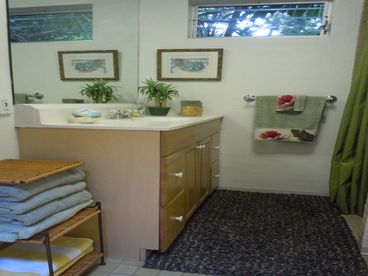 Bathroom has a tiled stall shower with vanity and a couple large mirrors.