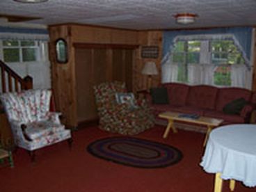 Livingroom has several overstuffed chairs and a couch.  Additional seating on the porch.