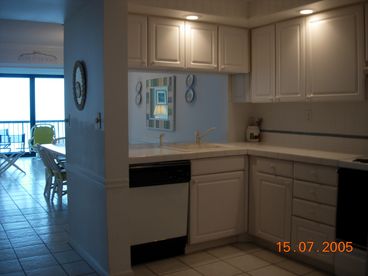 Spacious kitchen has tile counters with disposal, dish washer, oven and four burners, refrigerator and microwave oven.