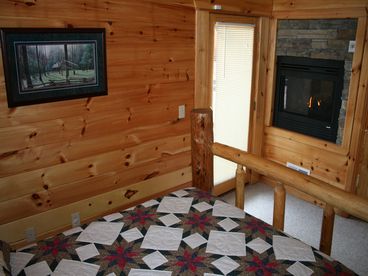 Upstairs master suite with Queen size log bed, double-sided gas fireplace, and private balcony