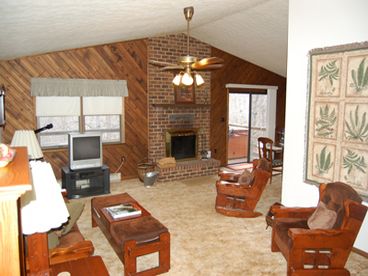 Gather with friends and family in the spacious living room with cathedral ceilings and large brick wood burning fireplace (wood provided)
