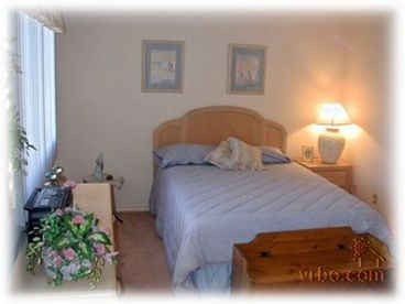 Master bedroom with queen-sized bed. View of pool and playground. - St. George Condo Rental
