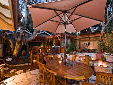 Patio table seating for six under a shade umbrella. Luxury hot tub, sunken gas fire pit, waterfall and koi pond.
