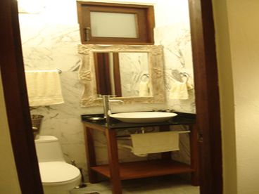 One of the bathrooms with marble tile and vessel sink.