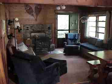 Living room with woodstove, sleeper sofa and loveseat, dining room table and benches