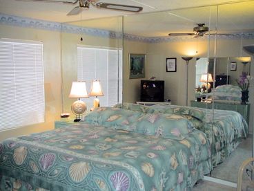 The bedroom features a king-sized bed and beautiful linens with a shell theme. Big windows let in natural light, while a 27 inch TV and DVD player provide entertainment. 

