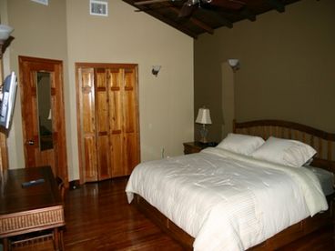 Master bedroom with king size bed and large bathroom with walk in shower, granite counters, and ceramic tiled floor. 