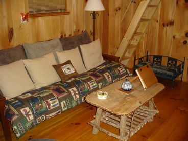 Living area with futon, stairs to bedroom and pet bed.