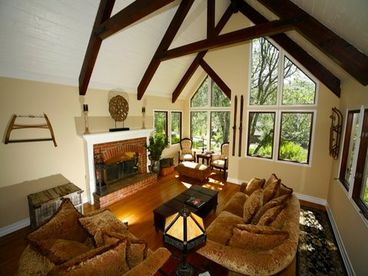 Cozy, large family room sitting next to a fireplace and Large windows that draws everyone in to enjoy the beautiful sunset and scenery. 