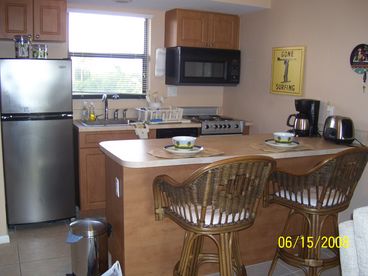 Kitchen features stainless steel appliances, 2 bar stools and breakfast bar