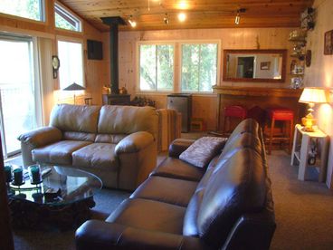 The living room faces the river with a wood burning stove and leather couches.