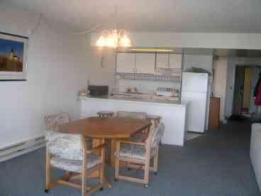 Fully equipped kitchen with eating bar and large dining area open to view.