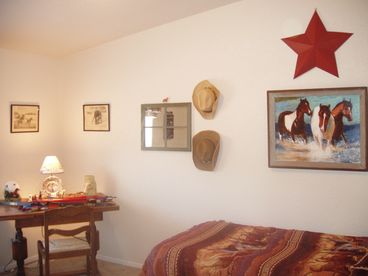 Western themed Bedroom wtih twin bed,  writing table and TV. 