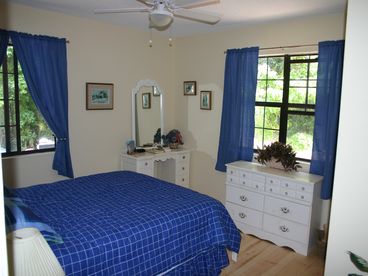 This is the main bedroom with a new Queen bed and includes a new ceiling fan. It looks out onto forested areas on both sides.