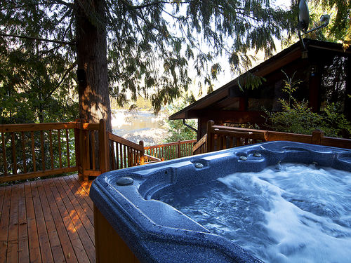 Private hot tub perched on the deck amongst pine trees has river view.