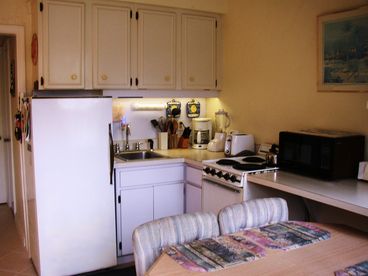 Kitchen view of a typical one-bedroom villa-the kitchen has all the comforts of home including all dishware, glassware, silverware, cookware, stove/oven, refrigerator, microwave, and coffee maker.