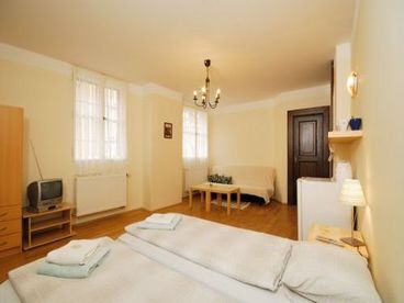 Studio with double bed, sofa, table, TV set, Internet and kitchenette corner.