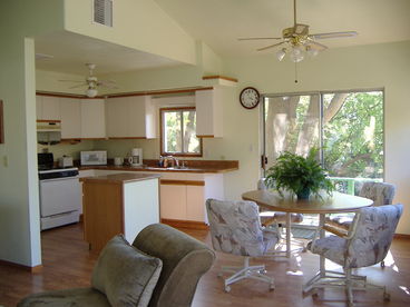 Fully equipped kitchen opens to dining area, back deck, garden views. 
